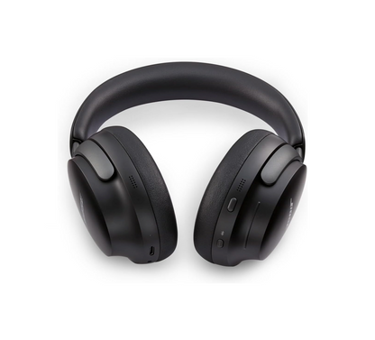 Eine Nahaufnahme von geschlossenen, mattschwarzen Bose QuietComfort Ultra Over-Ear-Kopfhörern mit gepolstertem Bügel, die auf weißem Hintergrund liegen. Die Außenseite der rechten Ohrmuschel zeigt sichtbare Steuerelemente.