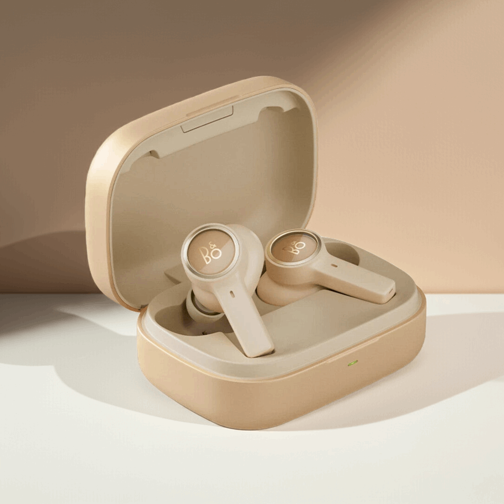 Bang & Olufsen BeoPlay EX True Wireless In-Ear-Kopfhörer in einer goldenen Farbvariante, platziert in ihrem geöffneten Ladeetui. Die Ohrhörer und das Etui haben ein monochromes, helles Finish mit einem leicht abgesetzten 'B&O'-Logo auf den Außenseiten.