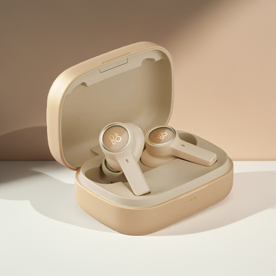 Bang & Olufsen BeoPlay EX True Wireless In-Ear-Kopfhörer in einer goldenen Farbvariante, platziert in ihrem geöffneten Ladeetui. Die Ohrhörer und das Etui haben ein monochromes, helles Finish mit einem leicht abgesetzten 'B&O'-Logo auf den Außenseiten.